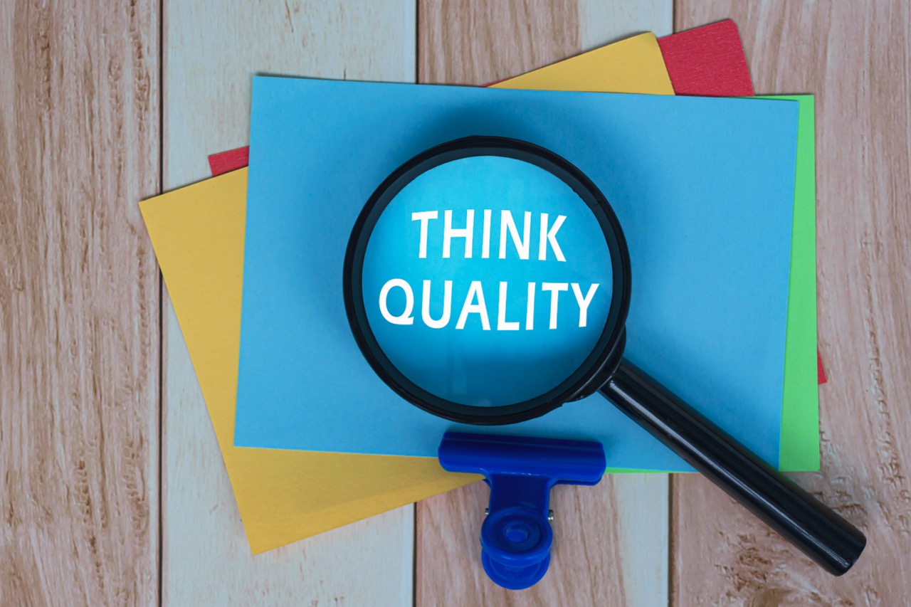 Requirements Of Clause 7- Think Quality on Colorful Adhesive Note With Magnifying Glass On Wooden Desk. Business Concept.